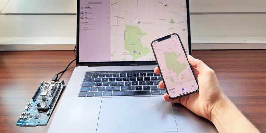 Ein Laptop mit einer Kartensoftware steht auf dem Tisch, davor hält eine Hand ein Smartphone. Bild: emergenCITY